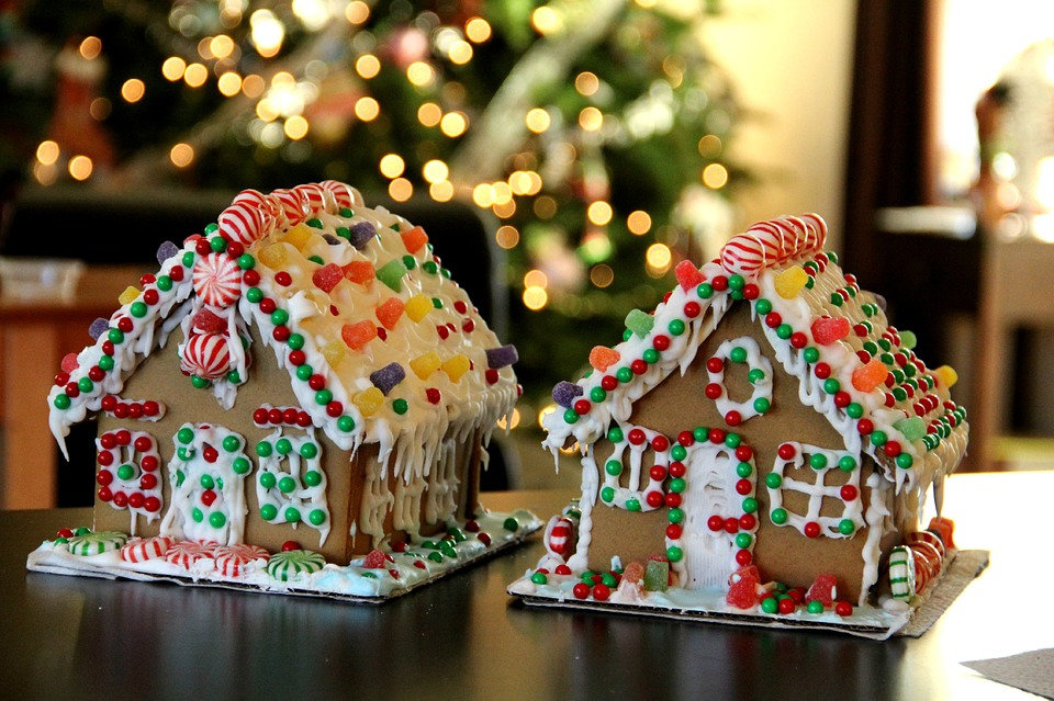 Gingerbread houses decorated with sweets beside a Christmas tree.